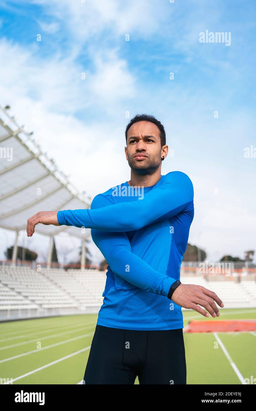Stock photo of african american male athlete standing on the track stretching his arms, Stock Photo