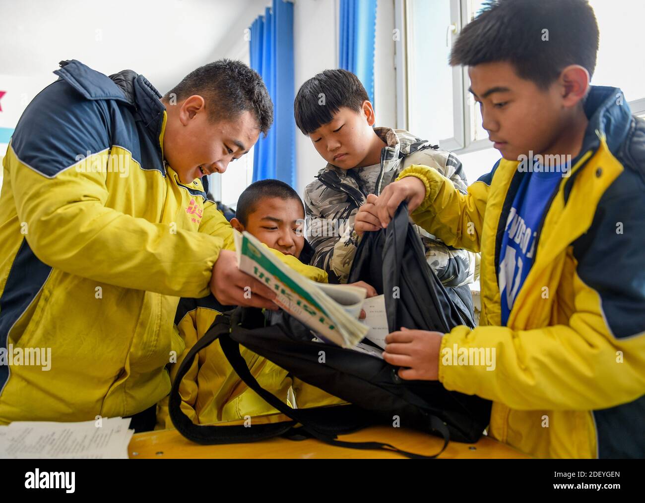 (201202) -- CHIFENG, Dec. 2, 2020 (Xinhua) -- Sun Simiao (1st, L) and his classmates help Wang Aoran pack his schoolbag in the school at Chifeng City, north China's Inner Mongolia Autonomous Region, Nov. 25, 2020.  Wang Aoran, 15, has been disabled in action by creatine kinase abnormality since he was a child. When in the second grade of primary school, he received help from schoolmate Sun Simiao, who voluntarily began to carry him from the school gate to his classroom. He has been helping him ever since.       The two became inseparable best friends. They went to the same middle school, both Stock Photo