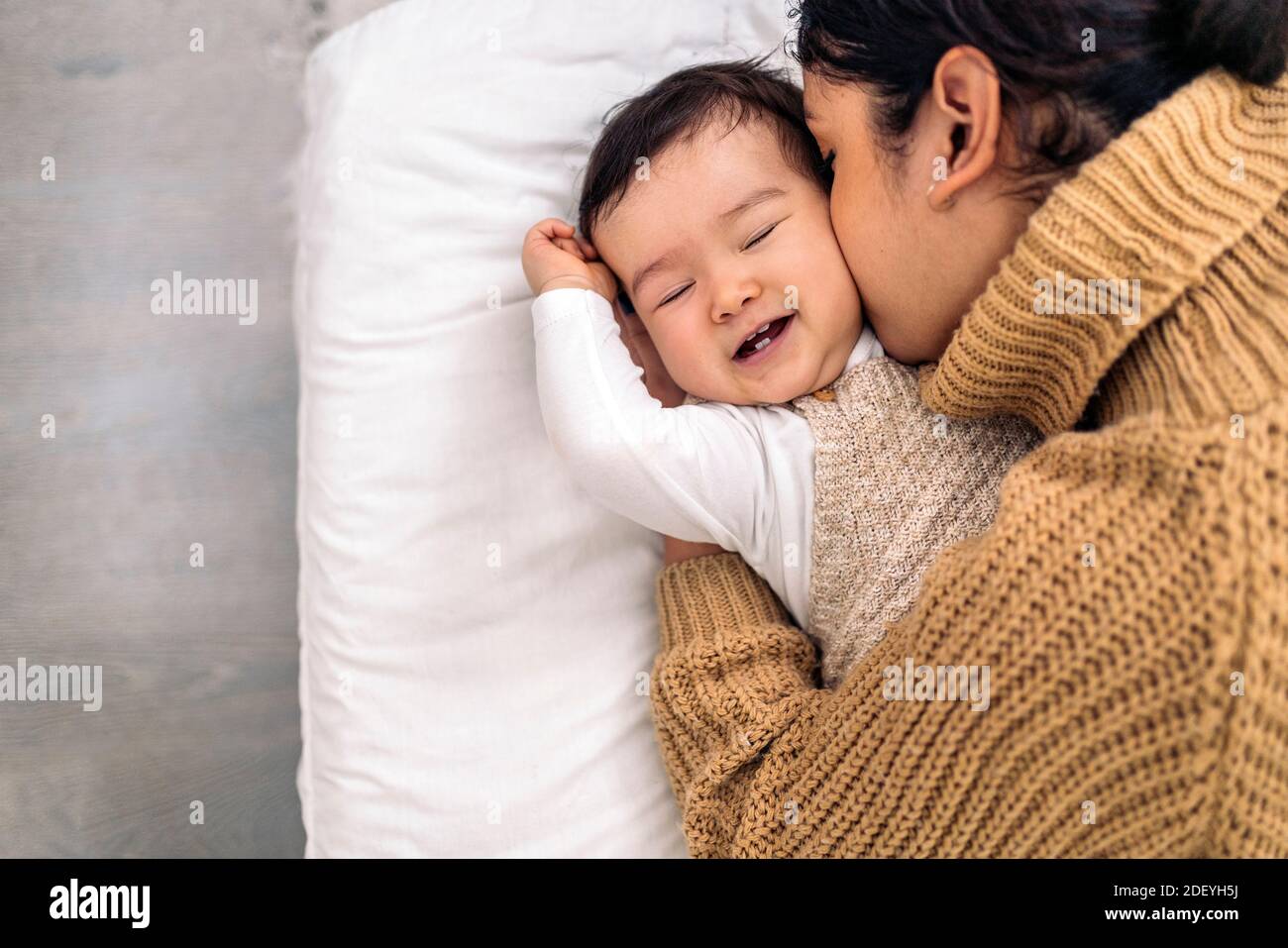 Stock photo of young mother kissing her little baby and sharing cute moment. Stock Photo