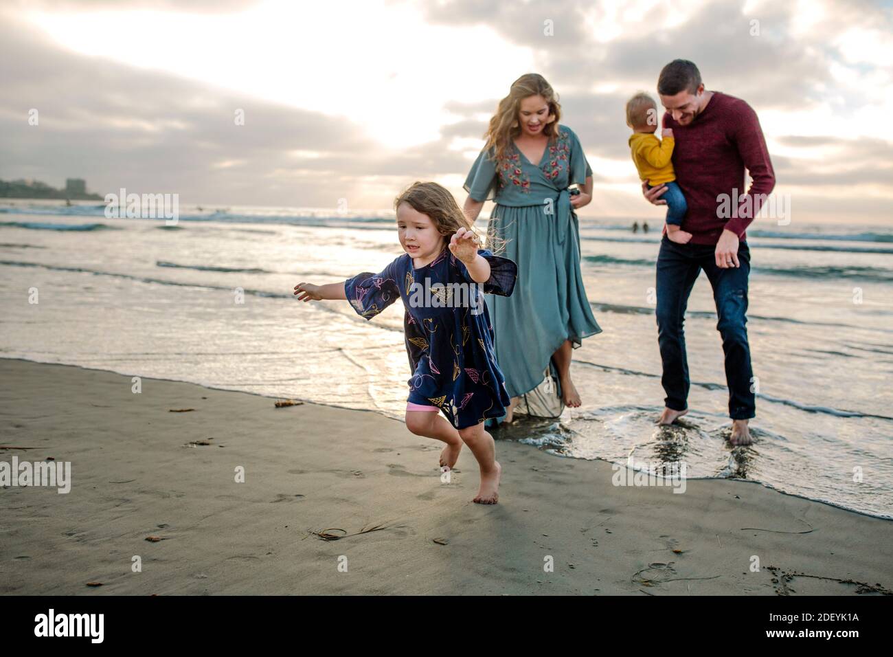 Young family with baby and 3 yr old girl wading in Pacific Ocean Stock Photo