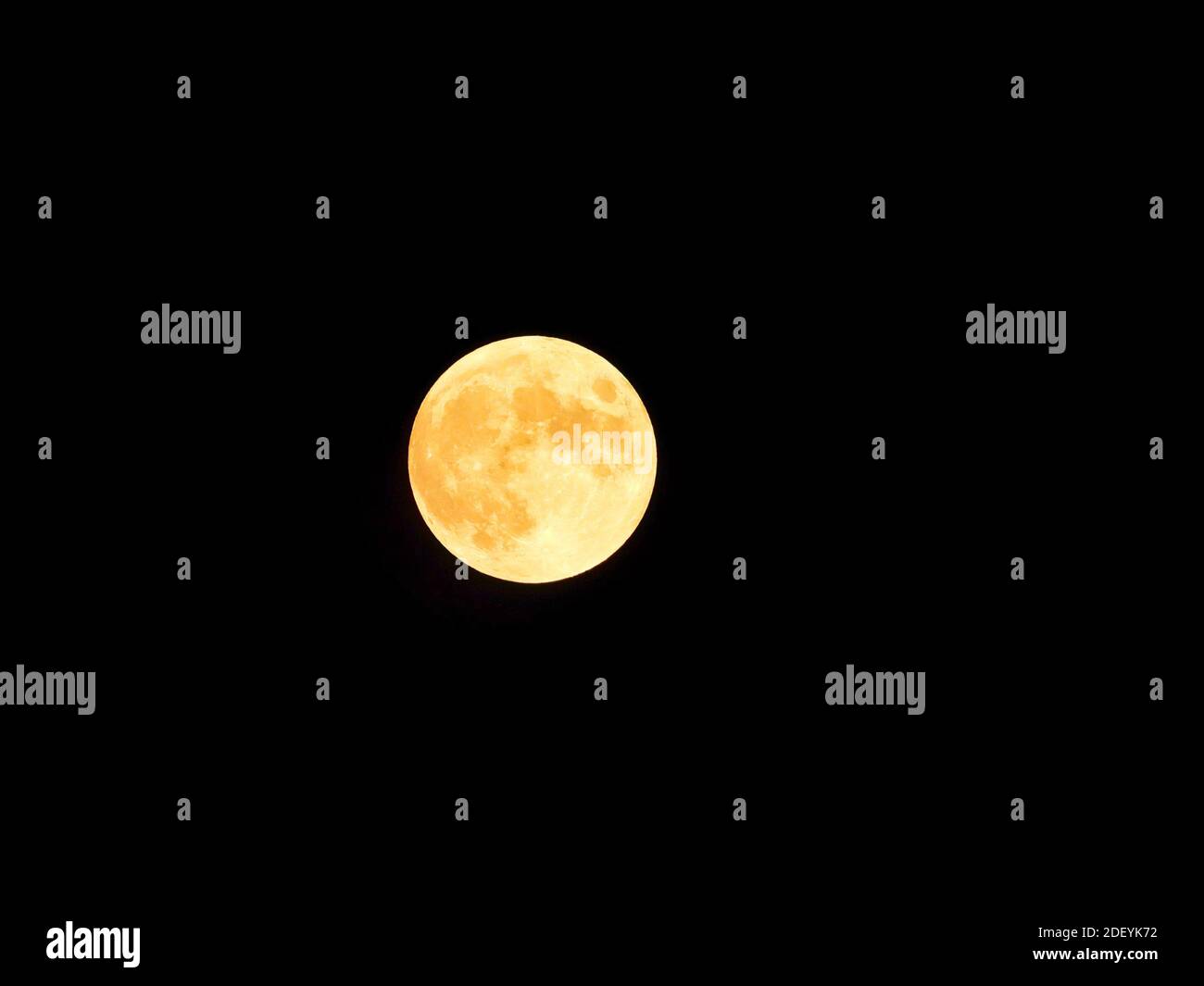 Full Moon Lights Up Dark Sky with Yellow Moon Light in Closeup of Full Moon Astronomy Stock Photo