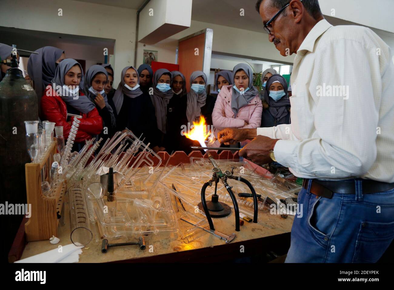 (201202) -- SANAA, Dec. 2, 2020 (Xinhua) -- Schoolgirls watch a technician making laboratory equipment in the General Administration for Educational Lab and Technology Production in Sanaa, Yemen, on Dec. 1, 2020. Young people in Yemen are looking forward to returning to school for higher education and a better future amid a lack of educational laboratories, new textbooks and teachers in many schools in the war-torn country.   TO GO WITH 'Feature: Yemeni youth aspire to return to school for higher education, better future' (Photo by Mohammed Mohammed/Xinhua) Stock Photo