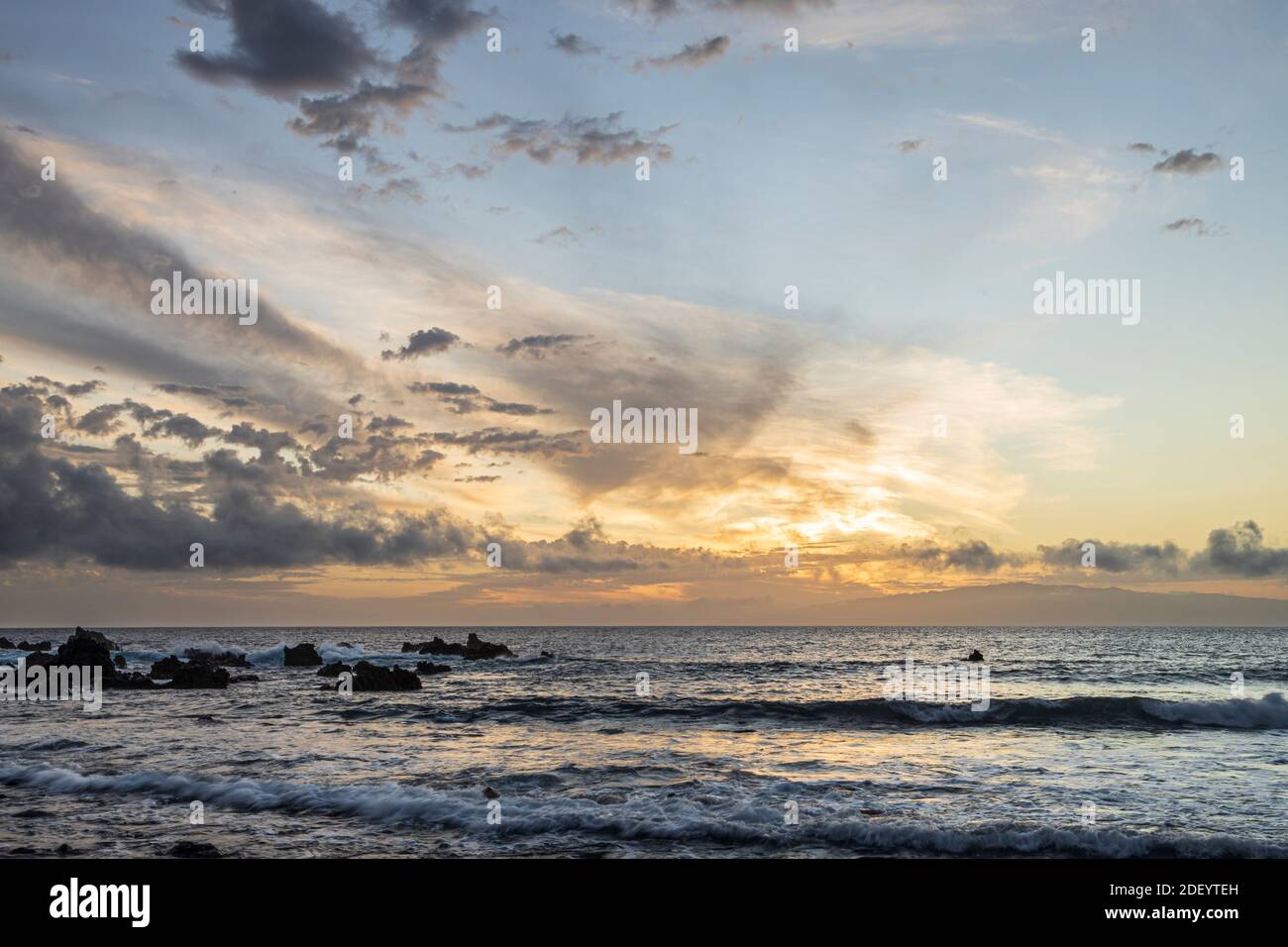 Mixed cirrus and cumulus clouds at different levels in the sky at sunset over the atlantic ocean, Playa San Juan, Tenerife, Canary Islands, Spain, Stock Photo