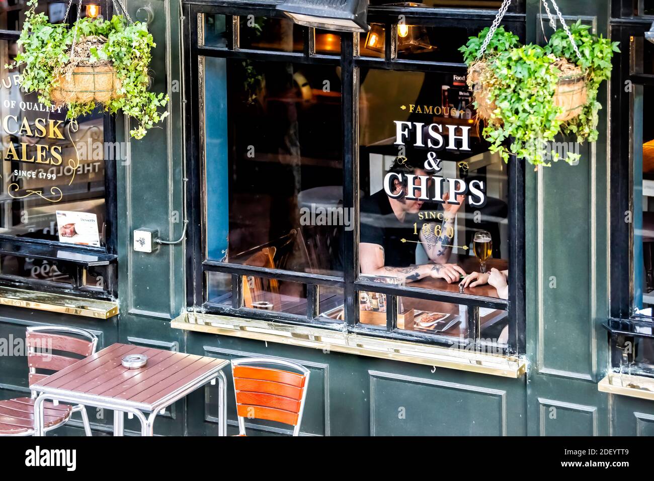 London, UK - June 22, 2018: French fries fish chips restaurant Greene King pub tavern bar restaurant sign on building exterior with people inside sitt Stock Photo