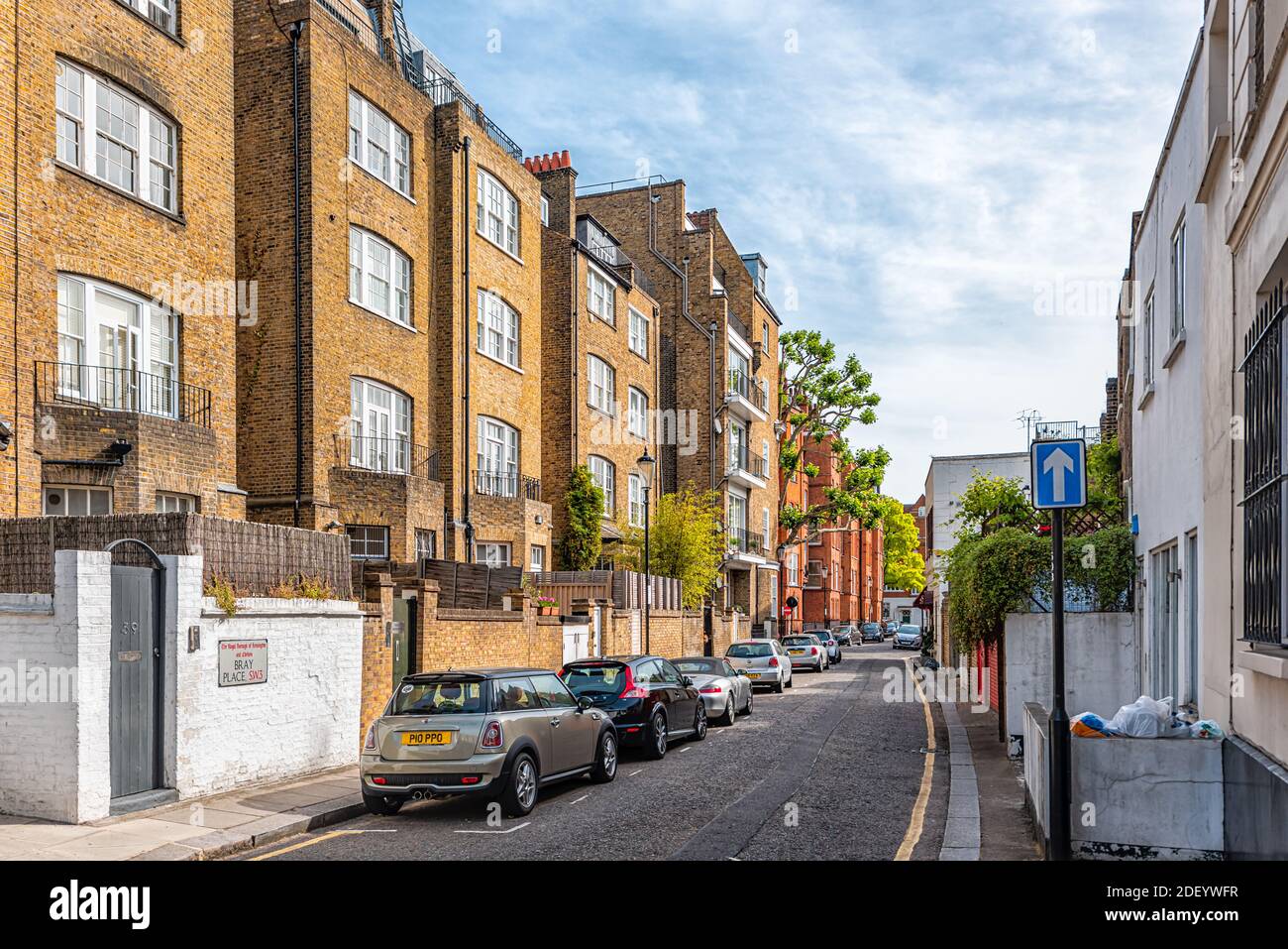 London, UK - June 24, 2018: Bray place street road in West Chelsea and Kensington neighborhood with red yellow brick terraced terrace townhouse, cars Stock Photo