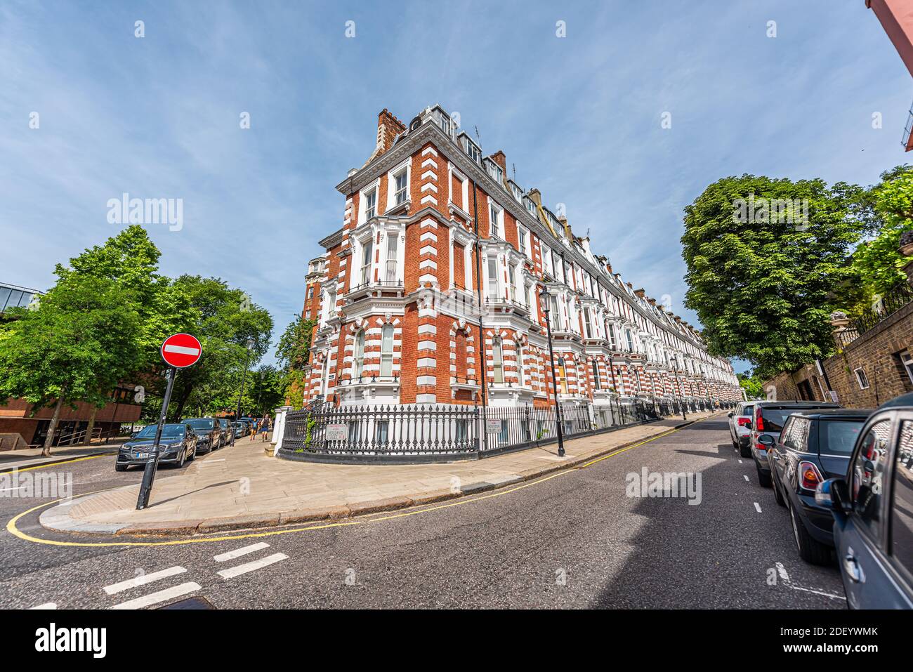 London, UK - June 24, 2018: White and red brick Victorian architecture residential apartment flat home town house on empty Hornton street road in Chel Stock Photo