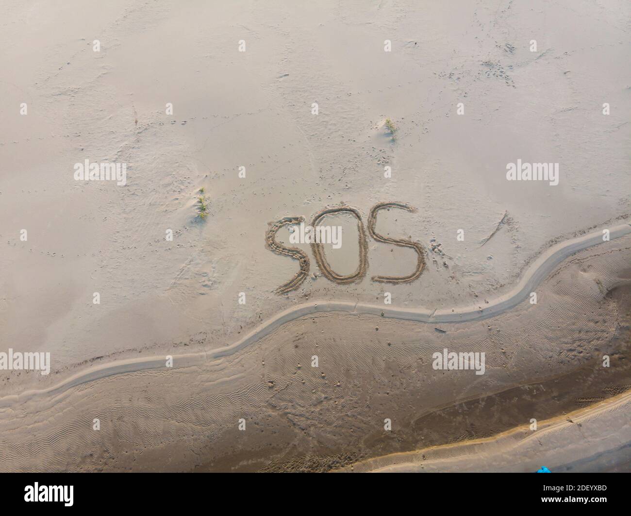 The letters SOS on the sand. The fragile nature asks for help Stock Photo
