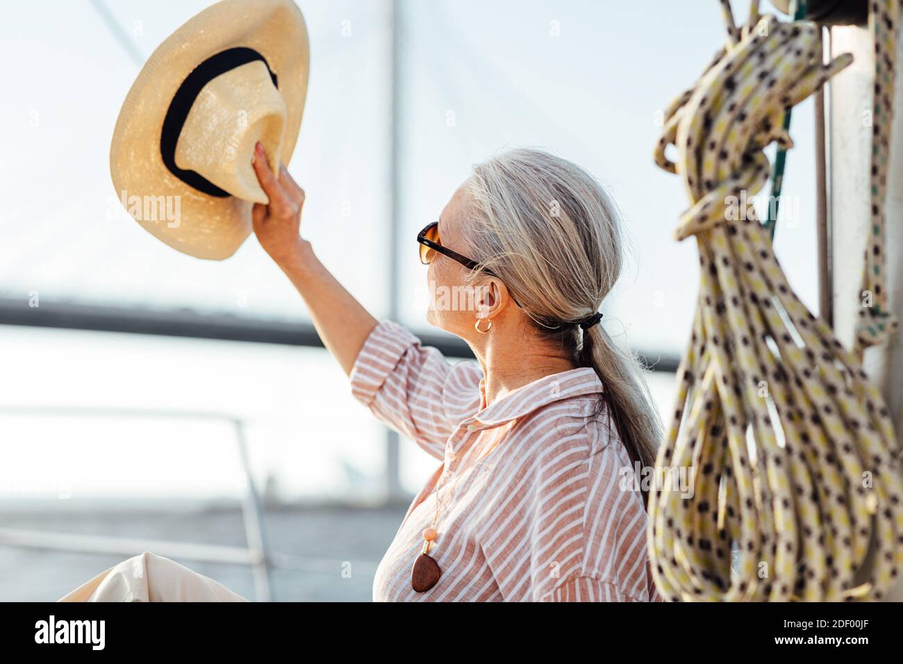 Woman on yacht uses a hat to hide her face from the sun Stock Photo