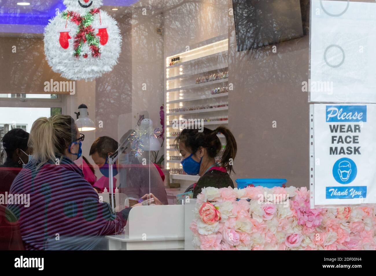 Nail bar with clients and staff working wearing face masks during the coronavirus covid-19 pandemic, December 2020, England, UK Stock Photo