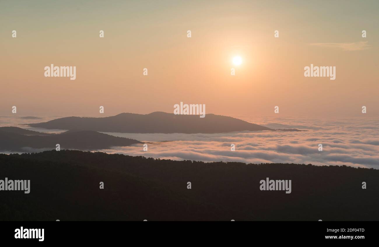 The sunrise burns off early morning fog in the Blue Ridge Mountains, Shenandoah National Park, Virginia. Stock Photo