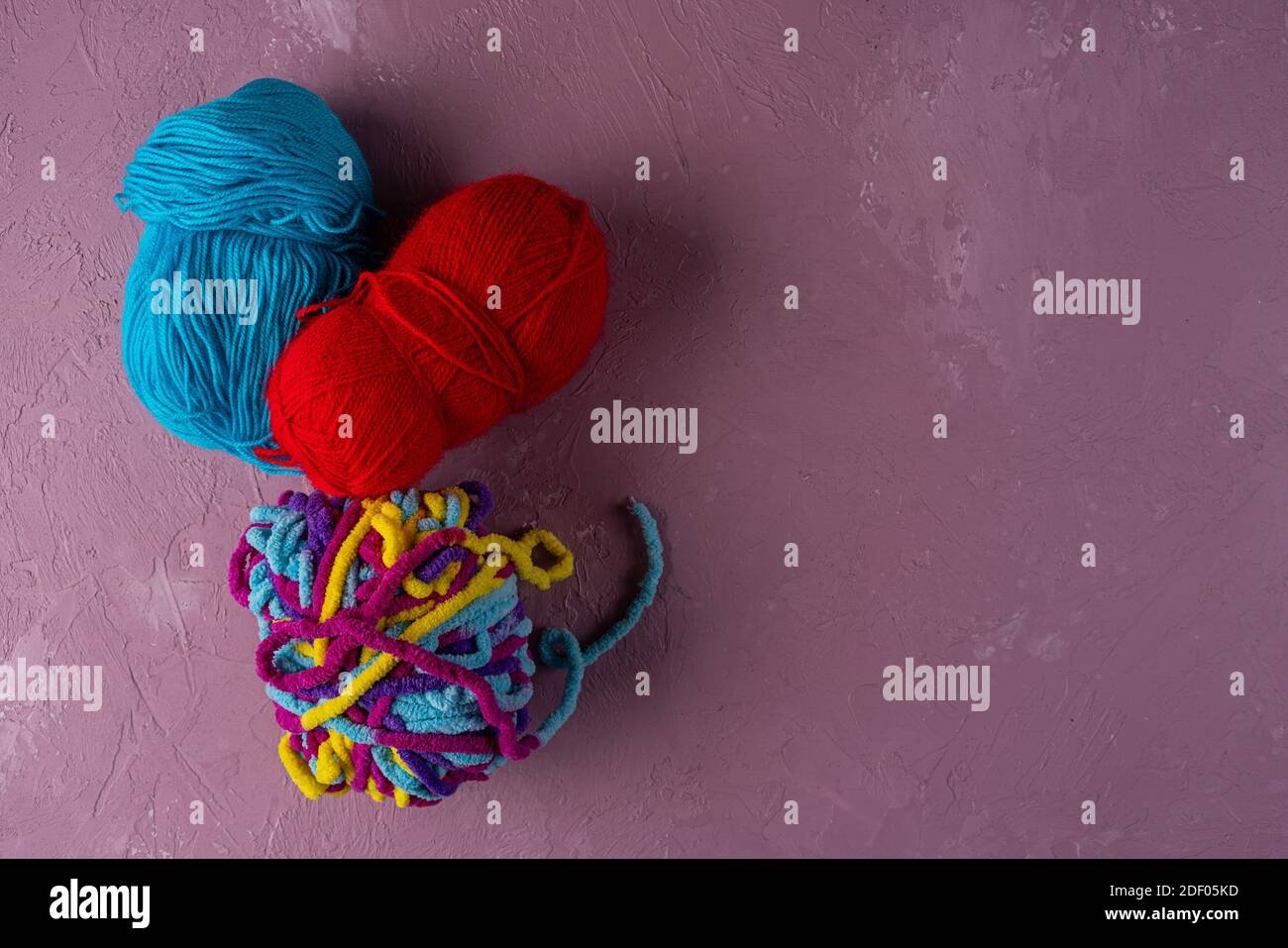 balls of multi-colored threads for knitting on a pink background Stock Photo