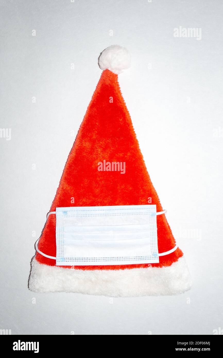 Red and White Plush Christmas Santa Hat with medical mask. Vertical top view Stock Photo