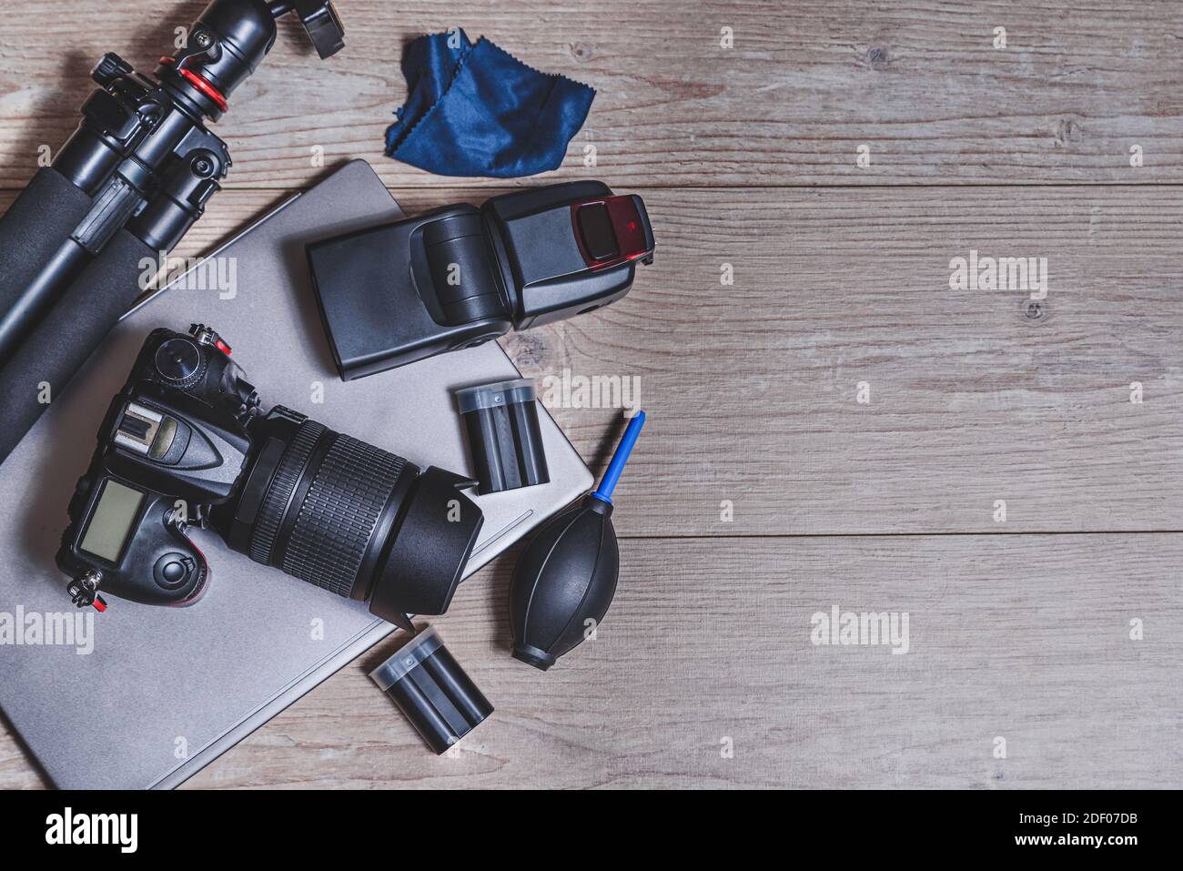 top view of a wooden table with photography equipment like digital professional camera, external flash unit, tripod, cleaning accessories and batterie Stock Photo