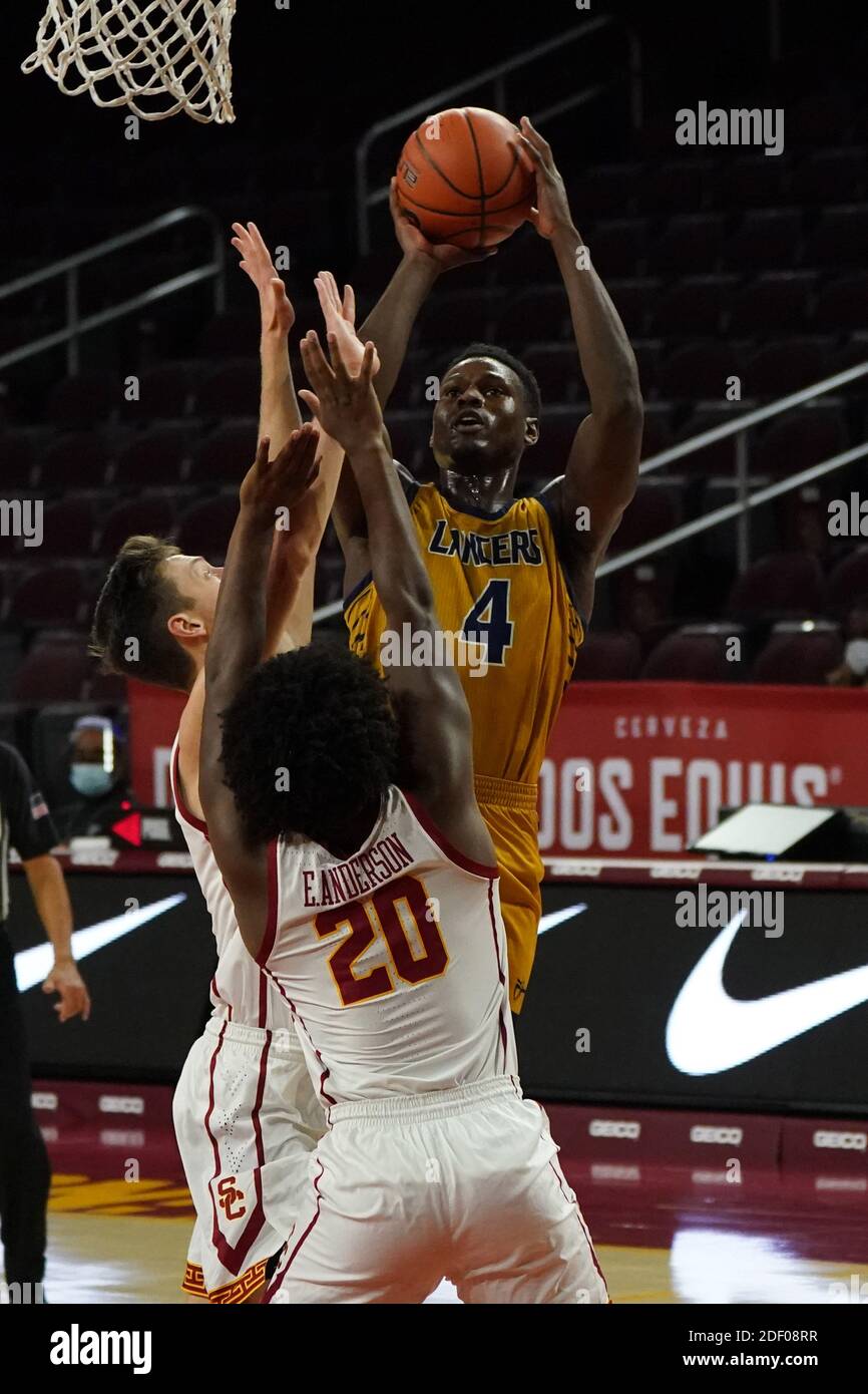 Cal Baptist Knights guard Elijah Thomas (4) shoots the ball as Southern California Trojans guard Ethan Anderson (20) and guard Drew Peterson (13) defe Stock Photo