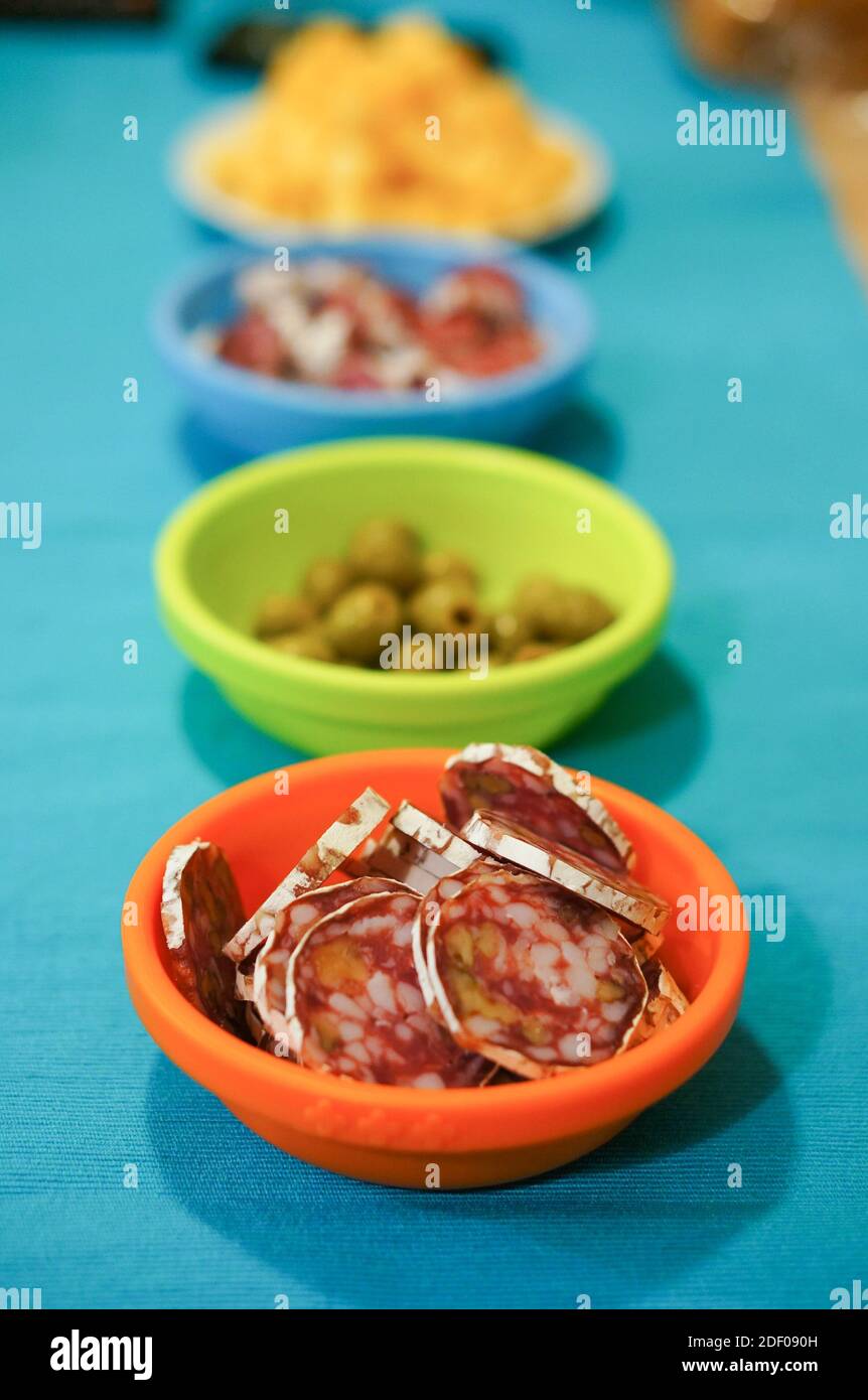 A vertical shot of a red plate with sausage slices and colorful plates