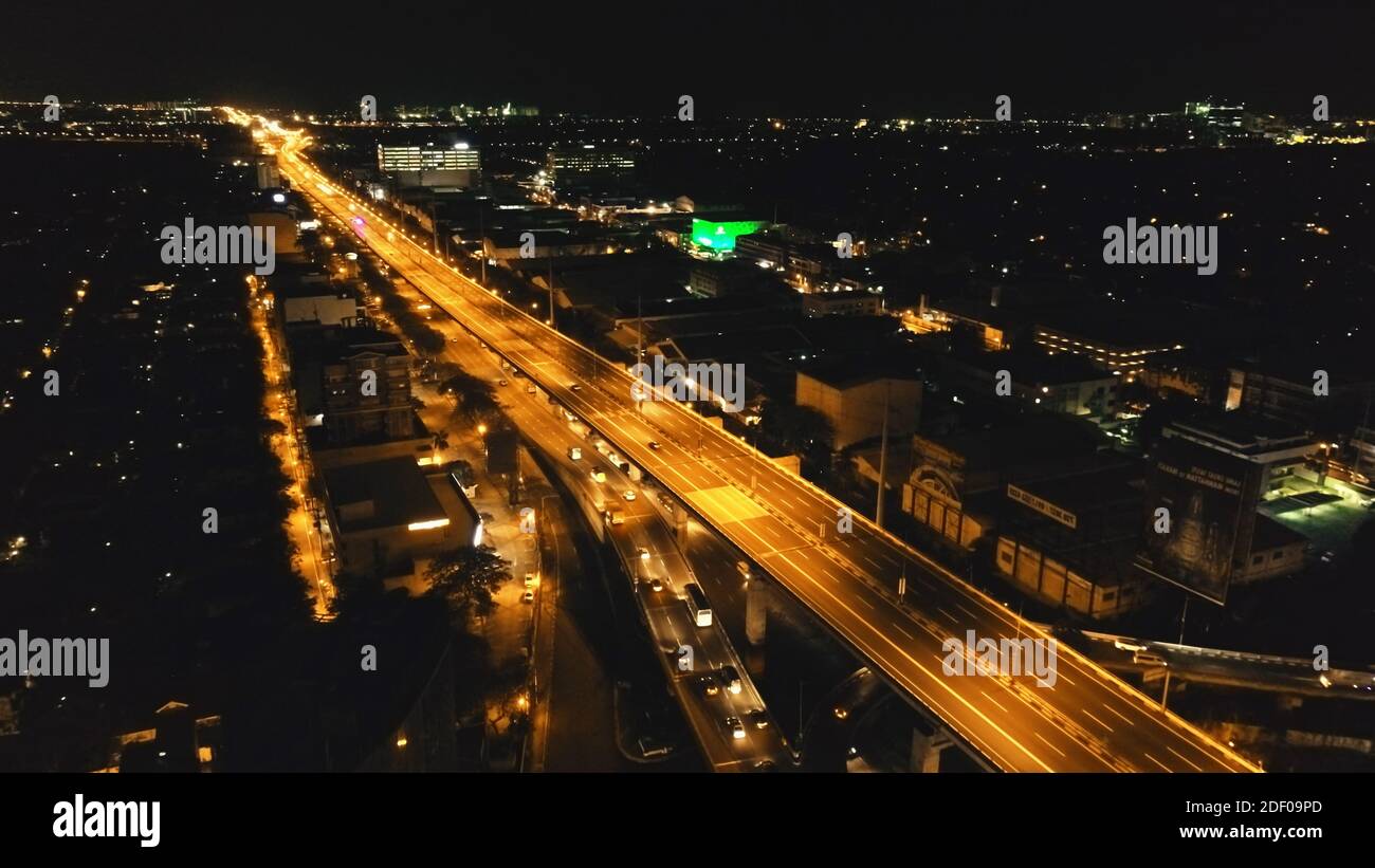 Closeup night traffic road with cars, trucks aerial. Philippines capital town of Manila cityscape. Urban scenery of metropolis city close up. Modern buildings with illuminated highway on bridge Stock Photo