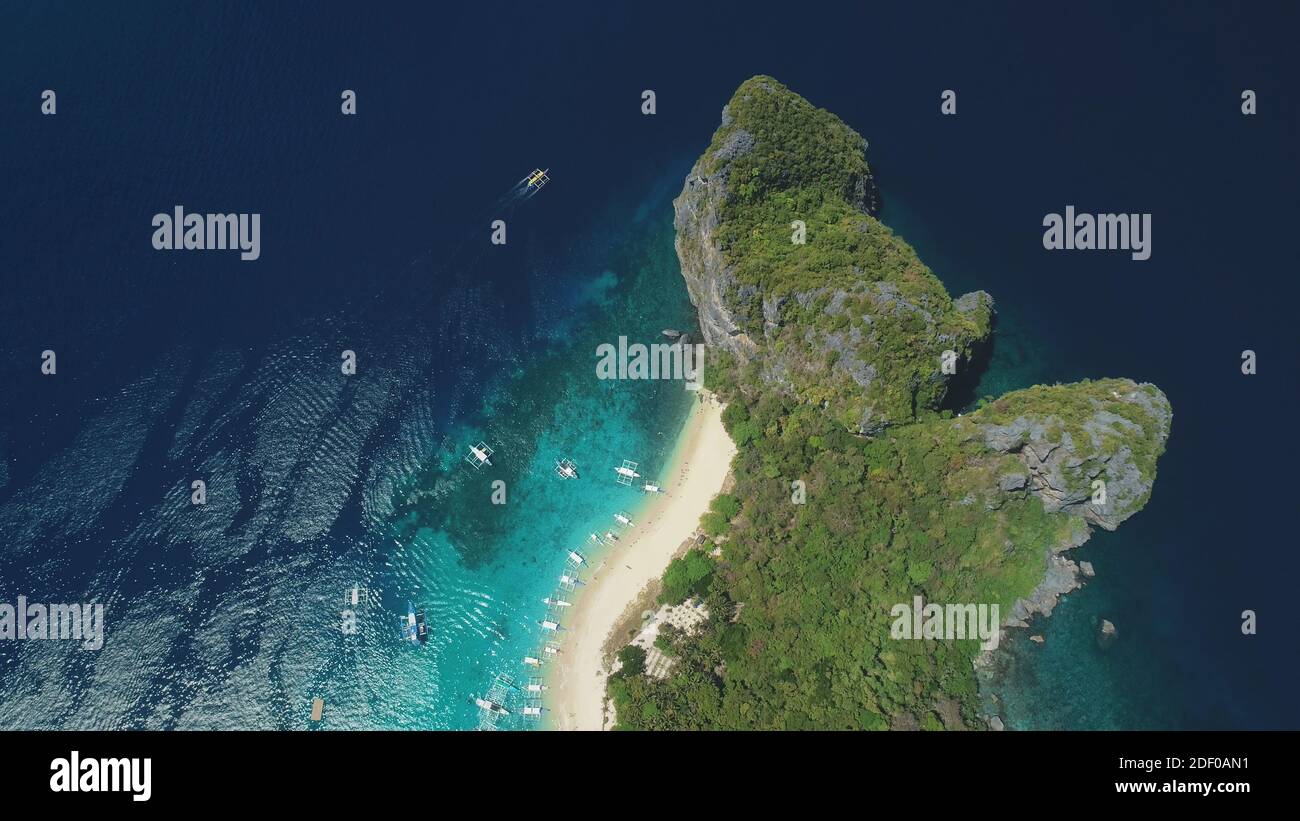 Top down ocean island aerial view. Tropical forest with palm trees on mount of Palawan isle, Philippines. Epic nature landscape of paradise resort at white sand beach. Asia sea bay drone shot Stock Photo