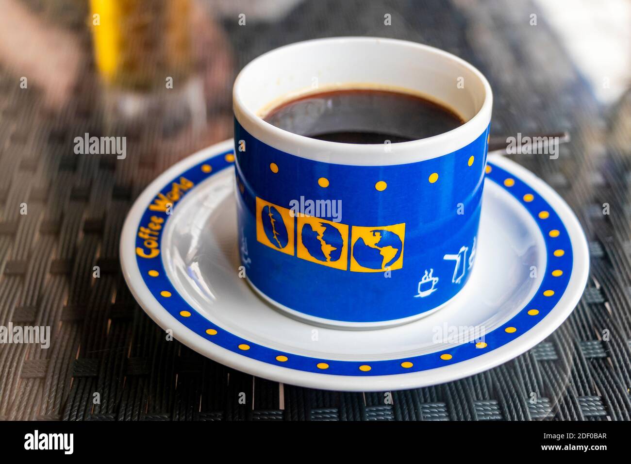 Black coffee in a blue cup with world globes, drunk in Thailand. Stock Photo