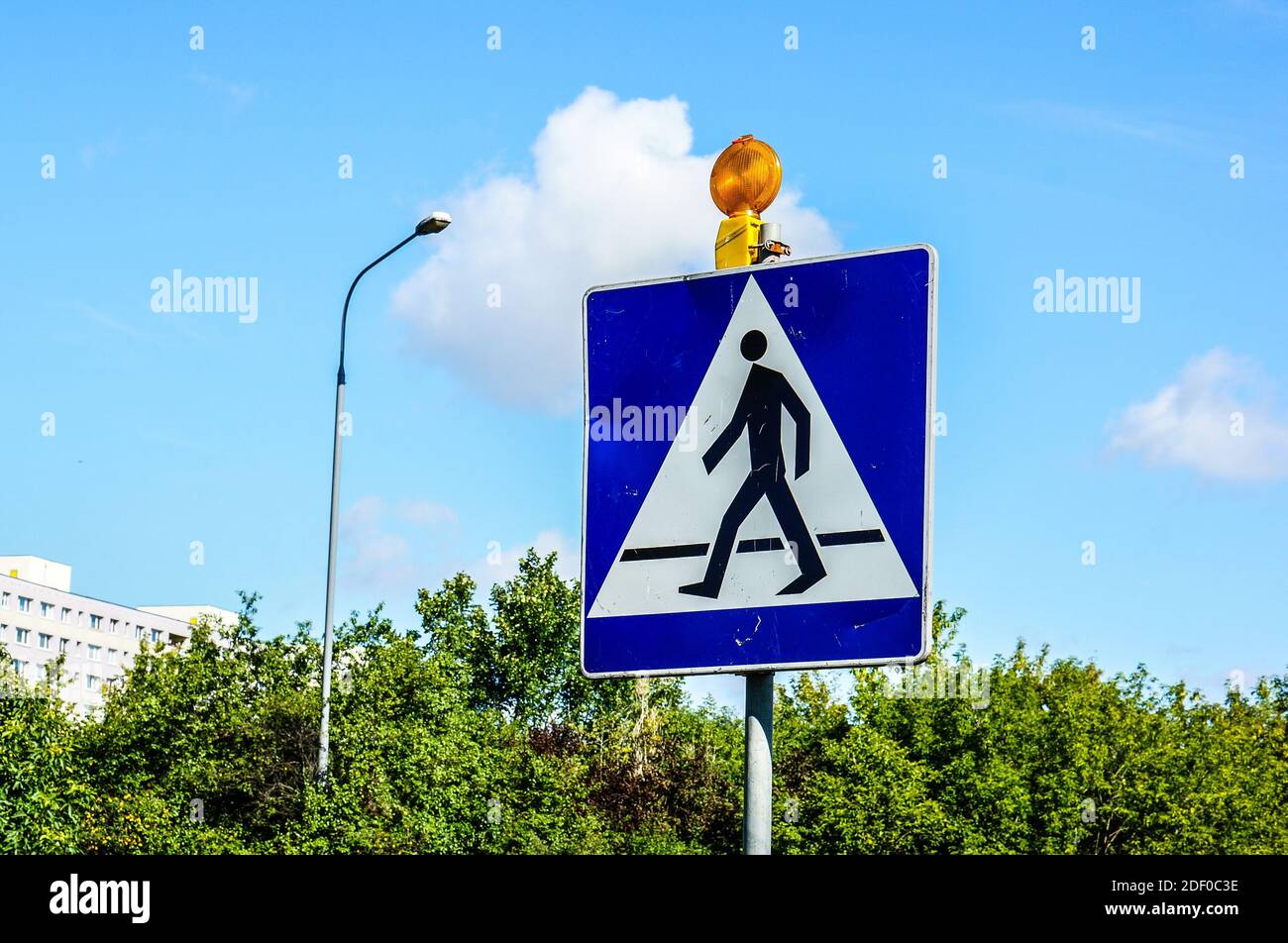 A Pedestrian crossing traffic sign with a cloudy blue sky in the ...