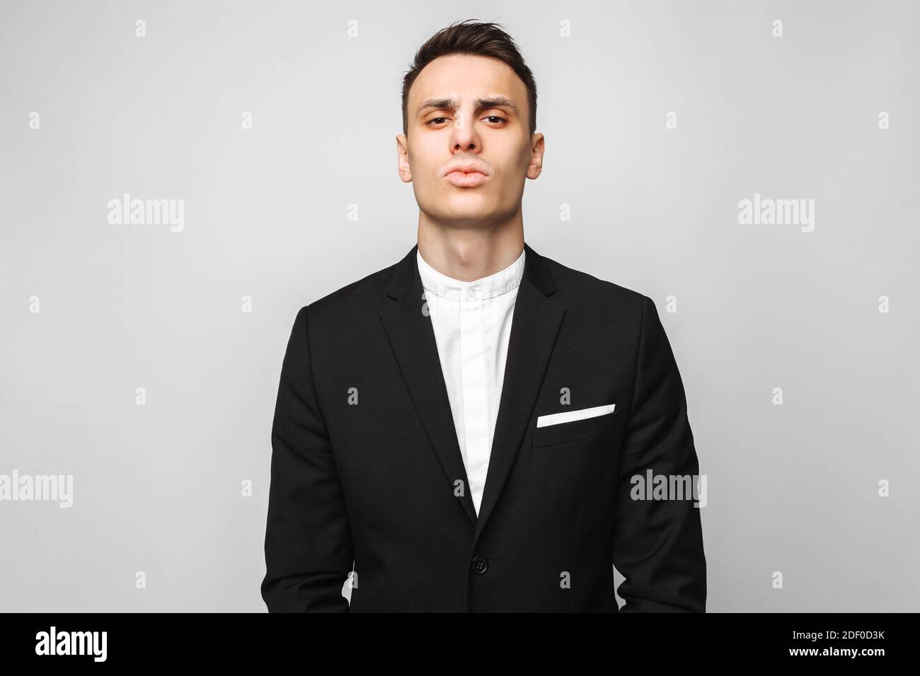 Portrait of a handsome young business man, male, in a classic black suit, on a gray background. Business concept, career. Stock Photo