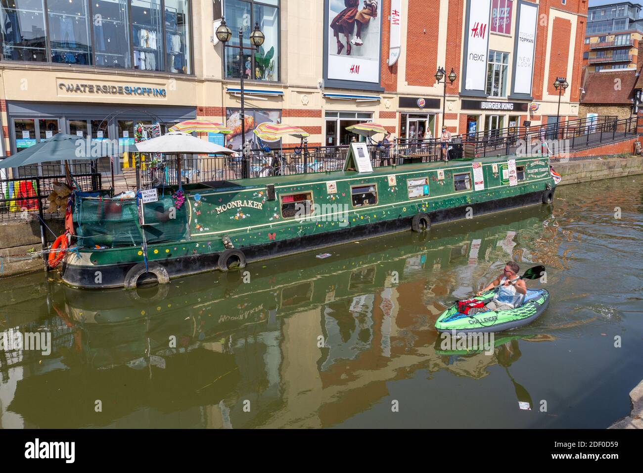 The River Witham with the Moonraker floating tearoom canal boat and a challenger kayak paddling past, Lincoln, Lincolnshire, UK. Stock Photo