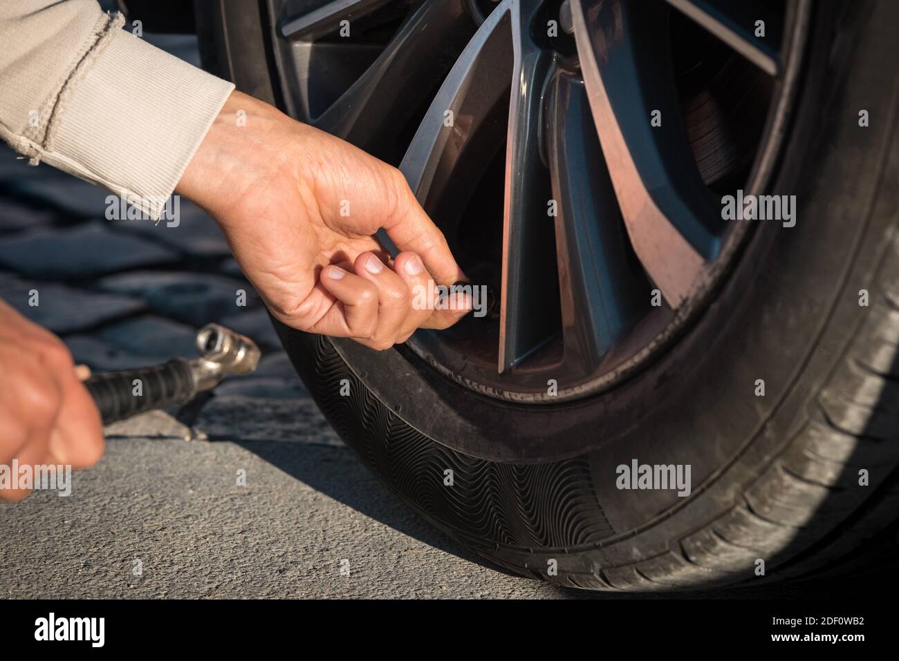 Close up of man hands inflating car tires. Tire air pressure checking before travel. Stock Photo