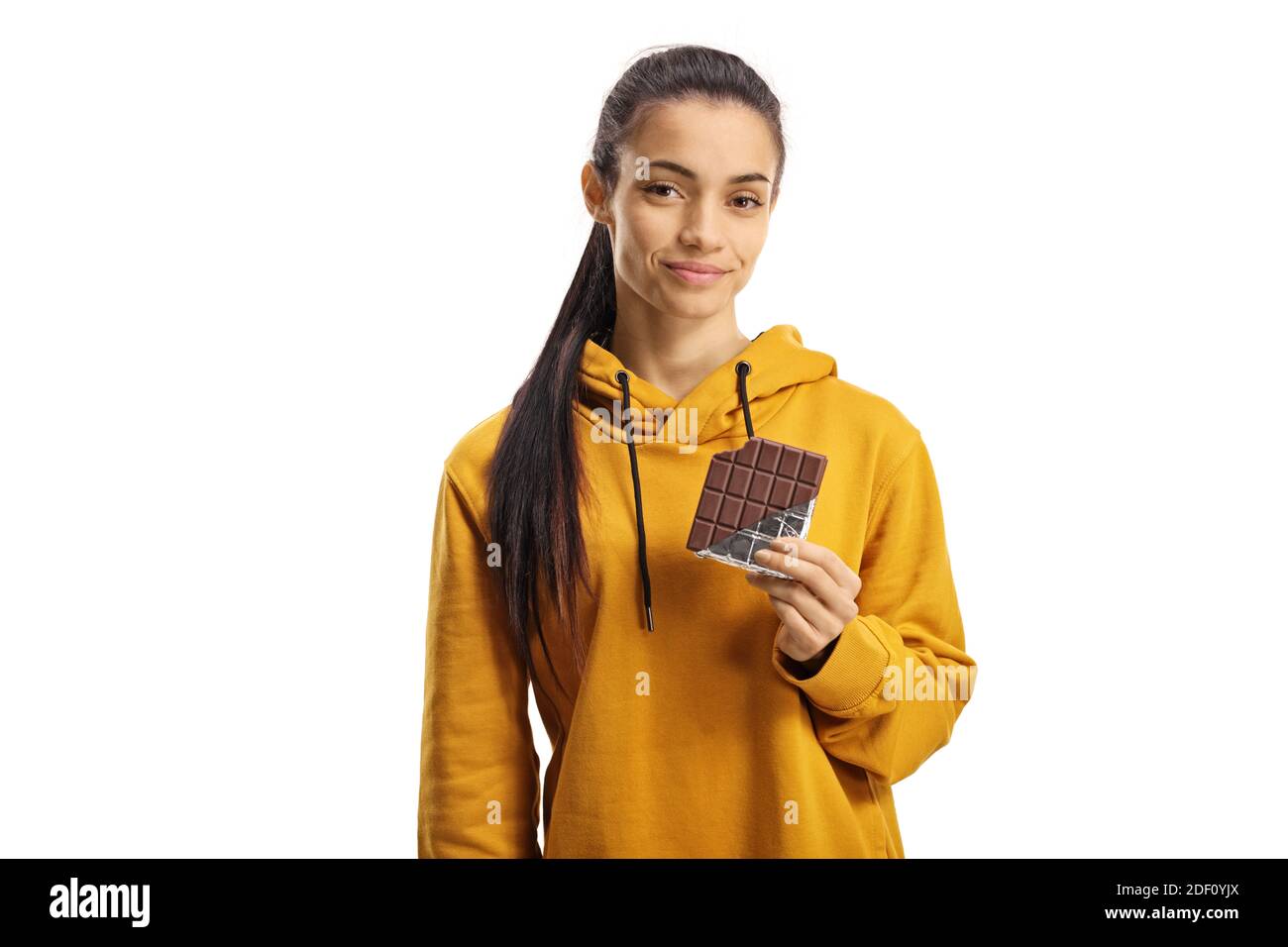 Young female in a yellow hoodie eating a chocolate isolated on white background Stock Photo