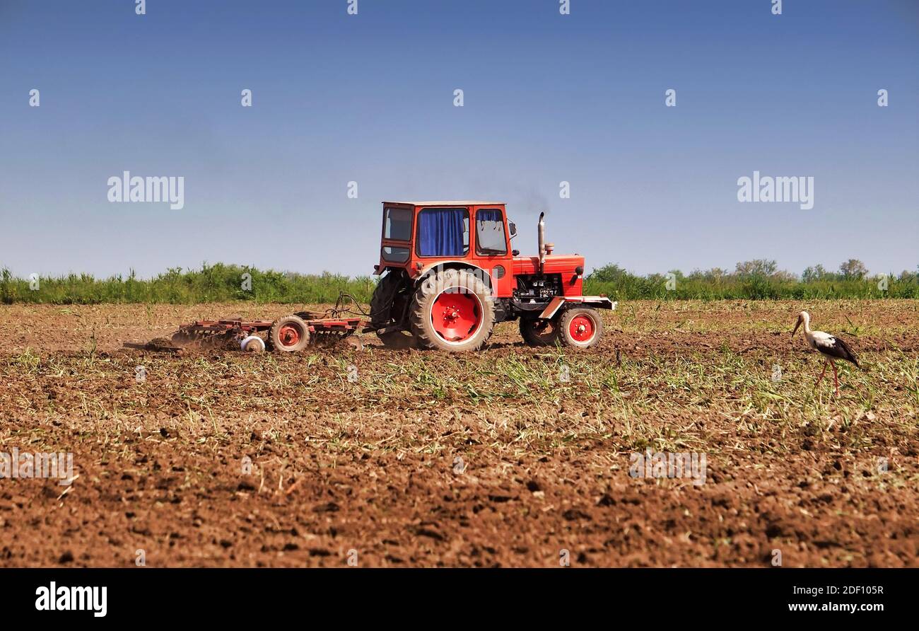 Tractor working farm land with disc harrow Stock Photo Alamy