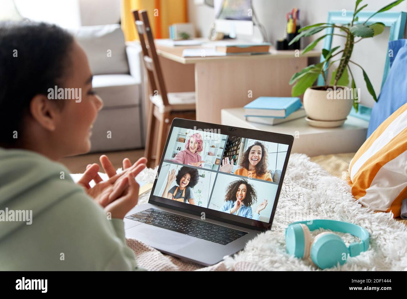 African teen girl talking with friends on distance video group call in bedroom. Stock Photo