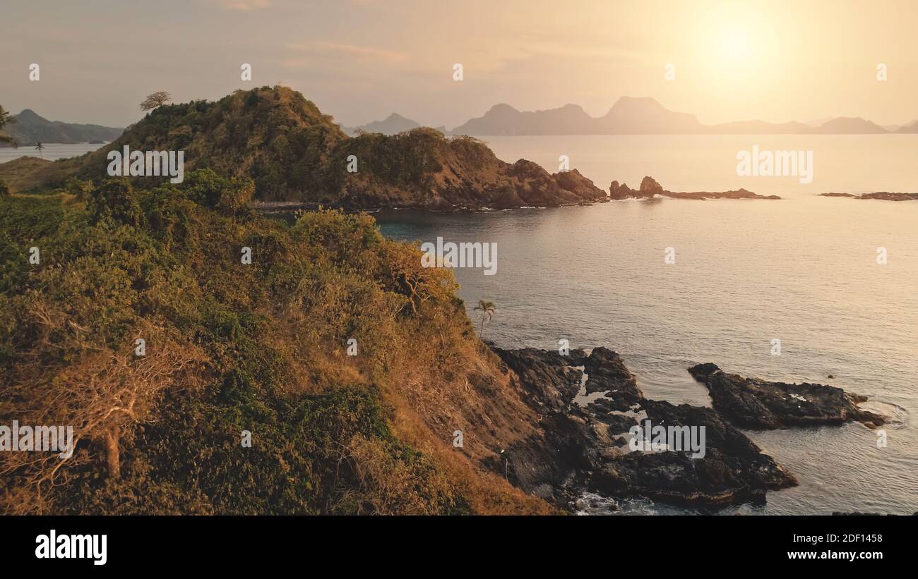 Closeup rock island at sun seascape aerial. Nobody tropic nature landscape with cliff mount in exotic trees and plants. Picturesque panorama of El Nido Islets at summer sunny day Stock Photo