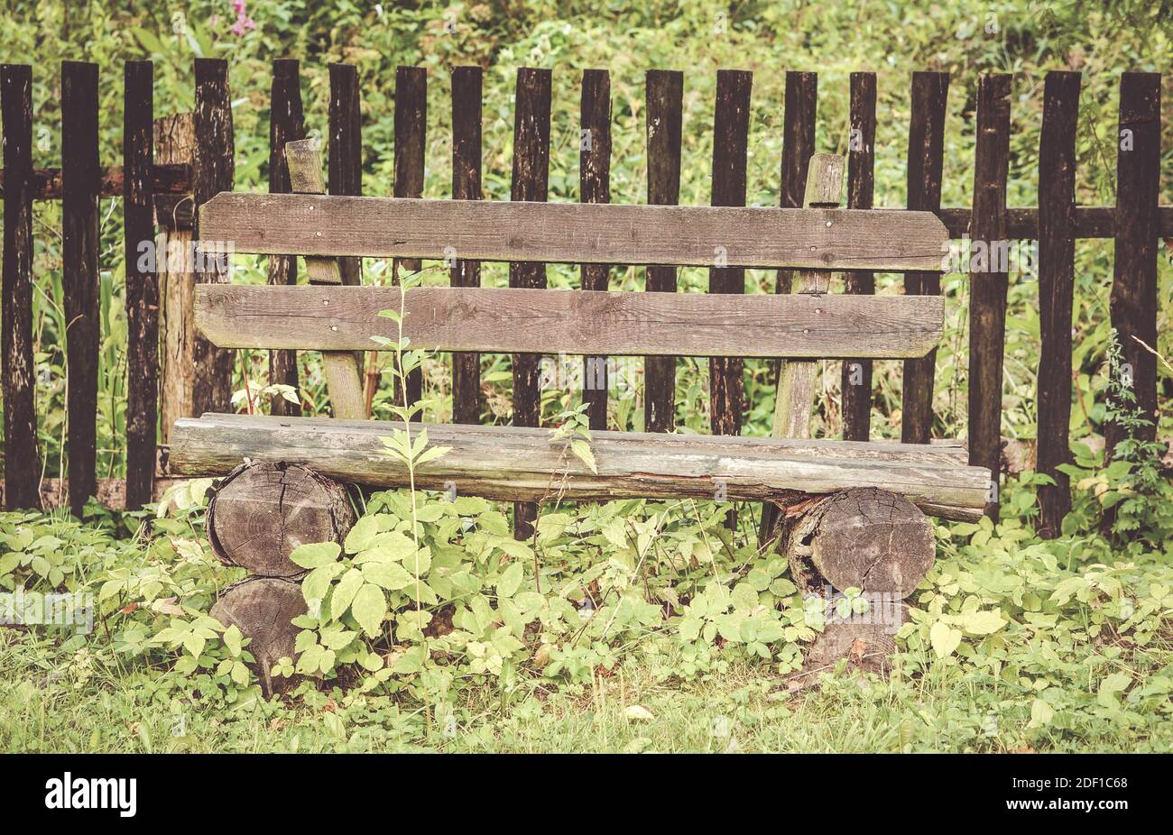 A closeup shot of a log bench beside a wooden fence in a grassy park ...