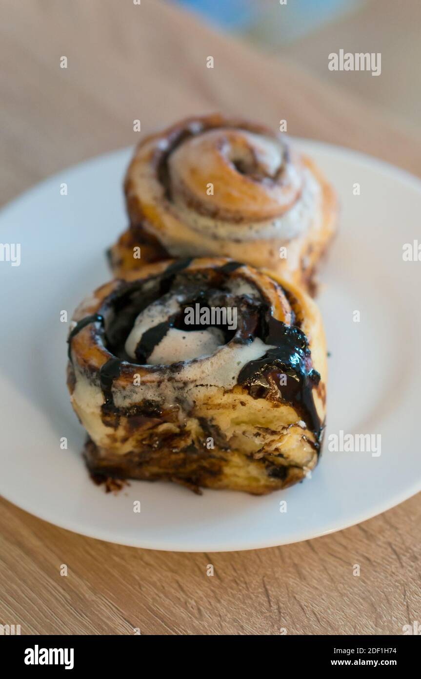 A closeup vertical shot of delicious cinnamon rolls on a white plate ...