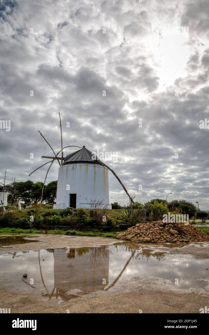 Windmill reflecting in a puddle with a dramatic sky in the background Stock Photo