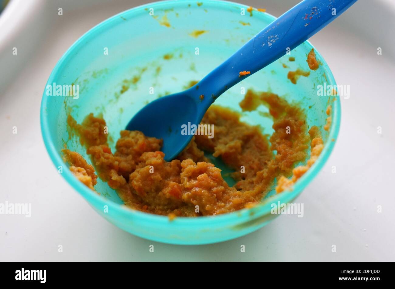 A closeup shot of a mash food with a plastic spoon and plastic bowl on a table Stock Photo