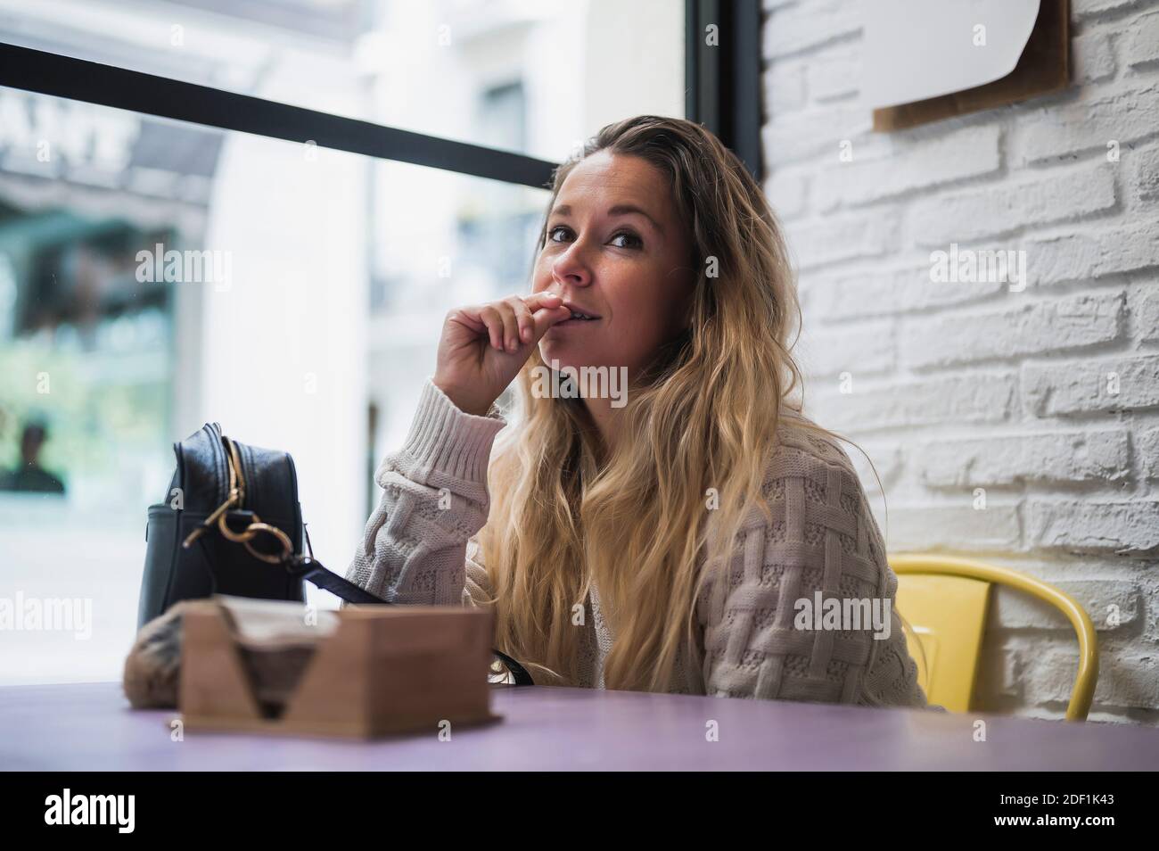 thoughtful woman sitting in cafe with a bag on the table and thinking about a plan for the future Stock Photo