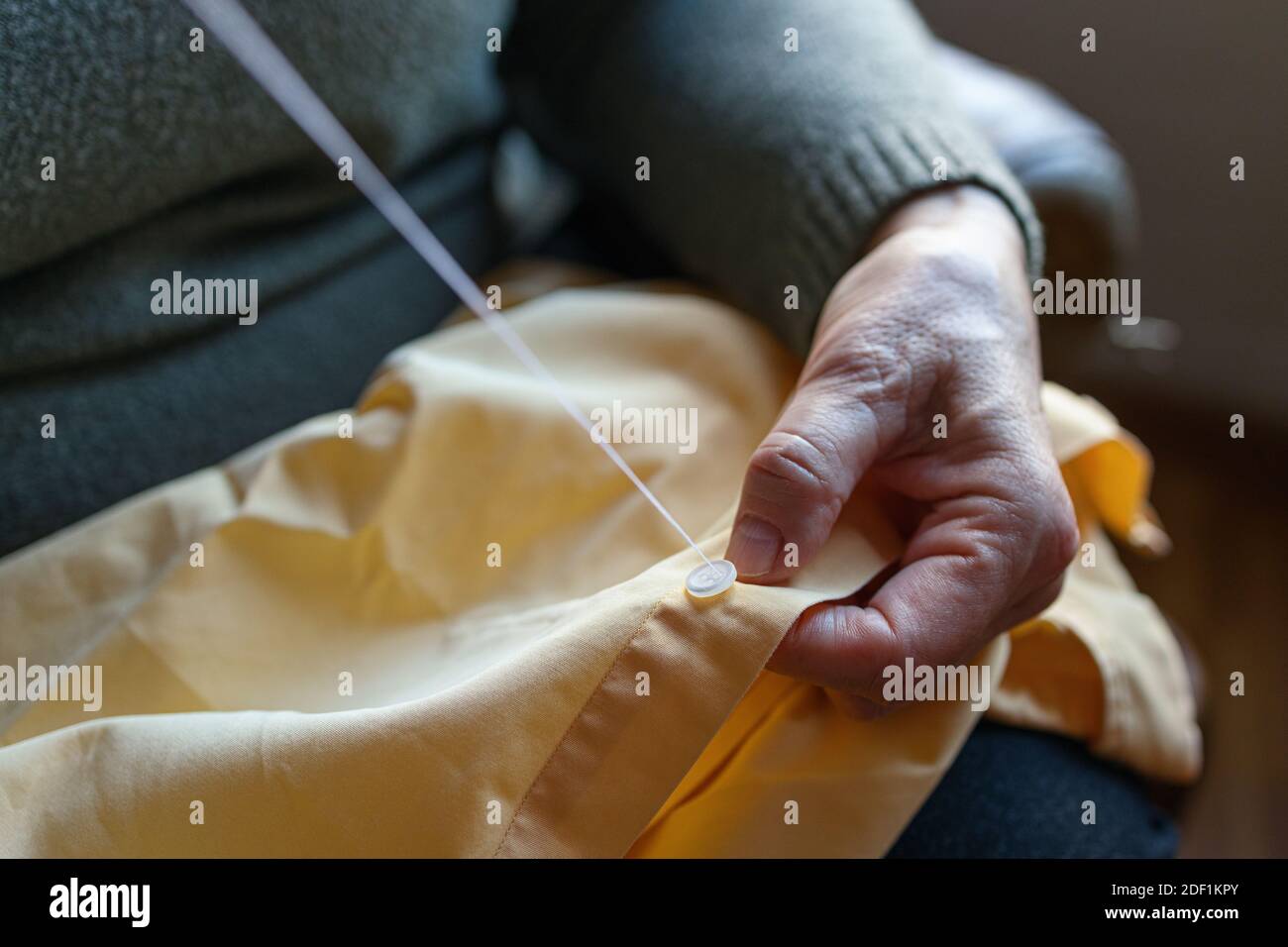 Old woman sewing a button at home Stock Photo - Alamy