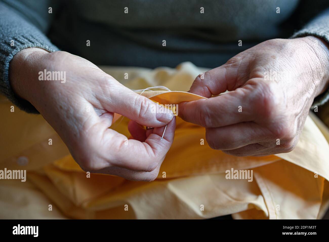 Old woman sewing a button at home Stock Photo - Alamy