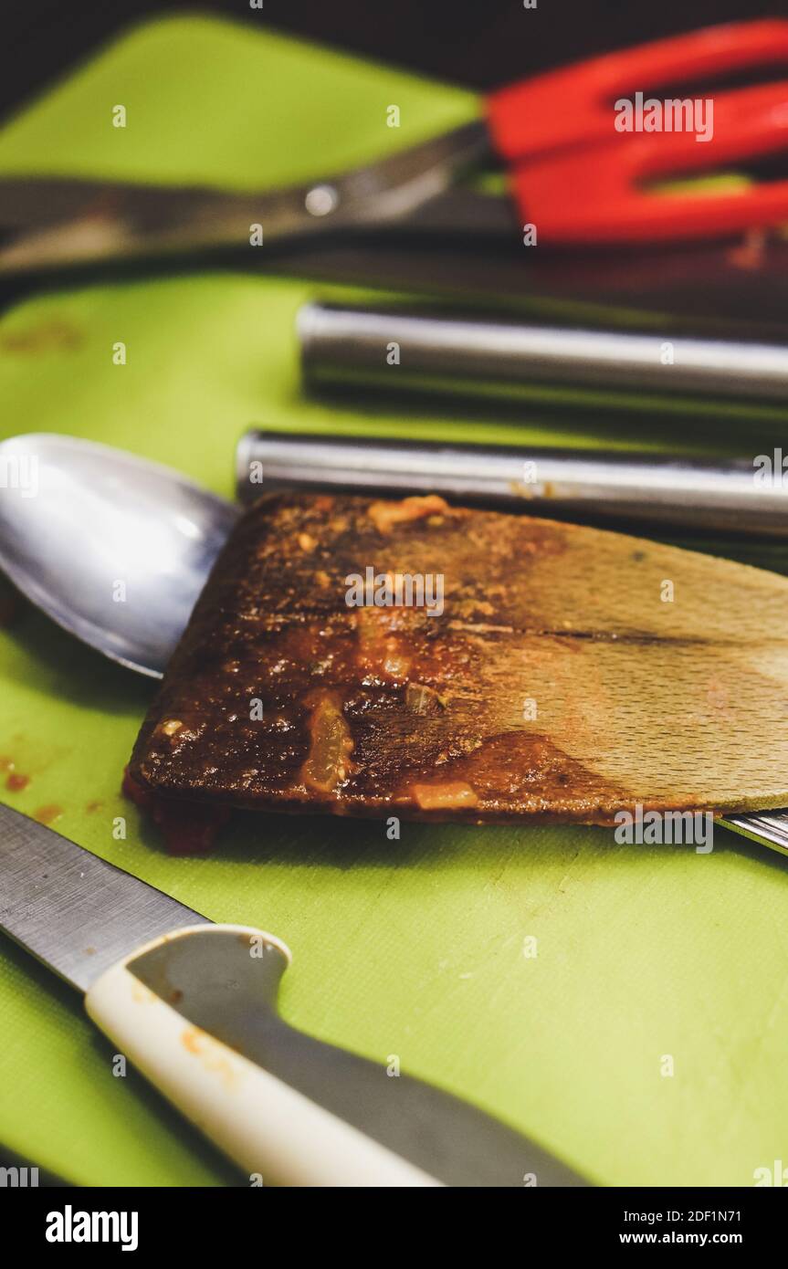 A greasy and burned wooden spatula next to other kitchen tools Stock Photo