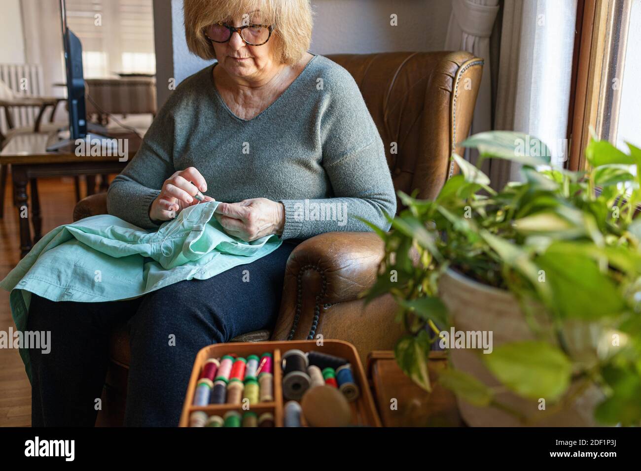 Old woman sewing at home Stock Photo