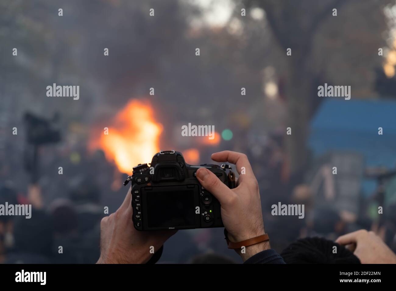 Paris, France - November 28th 2020 : at the march against the global security law, a person taking a picture while protesters are burning a trash can Stock Photo