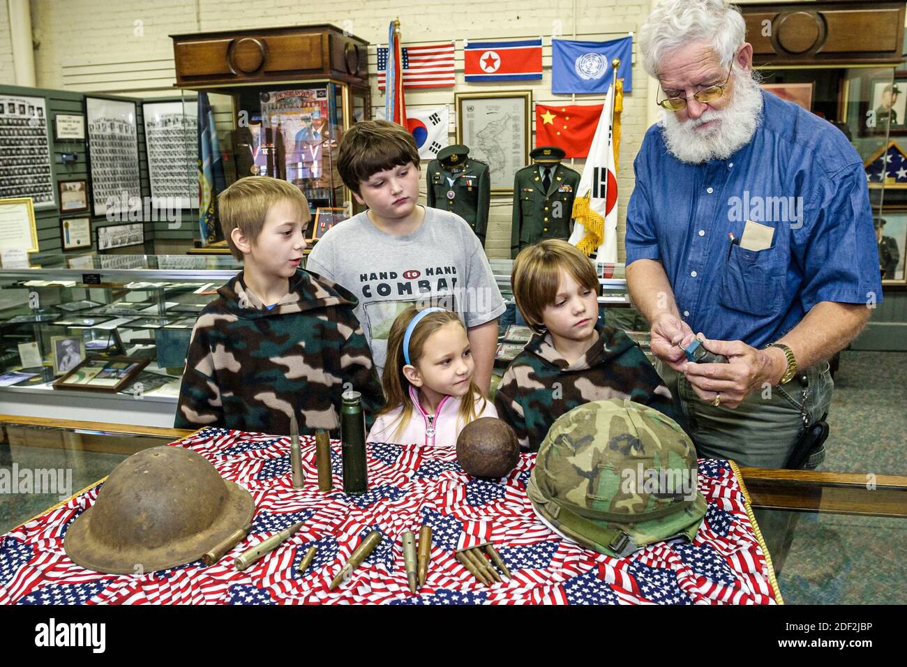 Alabama Athens Alabama Veteran's Museum & Archives,exhibits collection helmets ammunition shells,boys girl kids children,look looking man guide explai Stock Photo