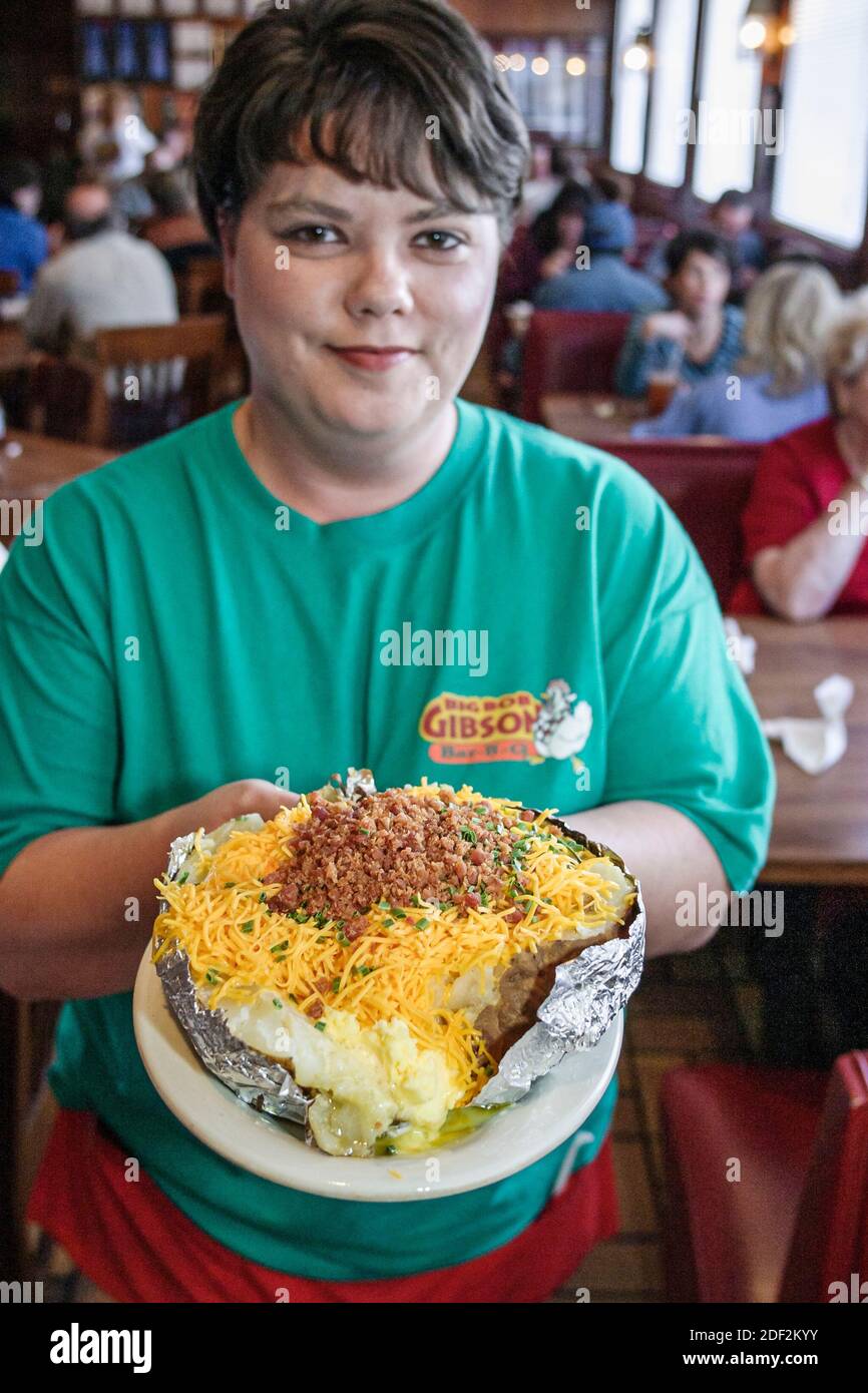 Alabama Decatur Big Bob Gibson BBQ restaurant,inside interior woman female waitress server serving pork beef chicken,bar-b-q stuffed baked potato, Stock Photo