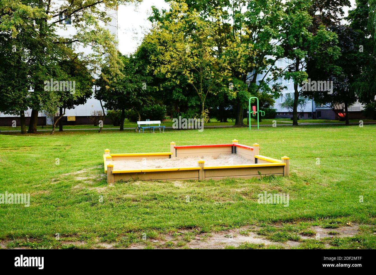 An area of sand in a green park surrounded by trees Stock Photo