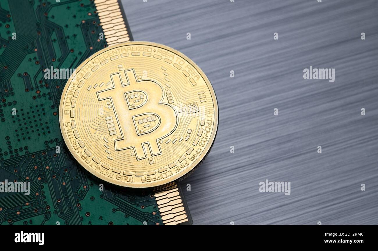 Bitcoin token on top of computer circuit board and brushed metal background Stock Photo