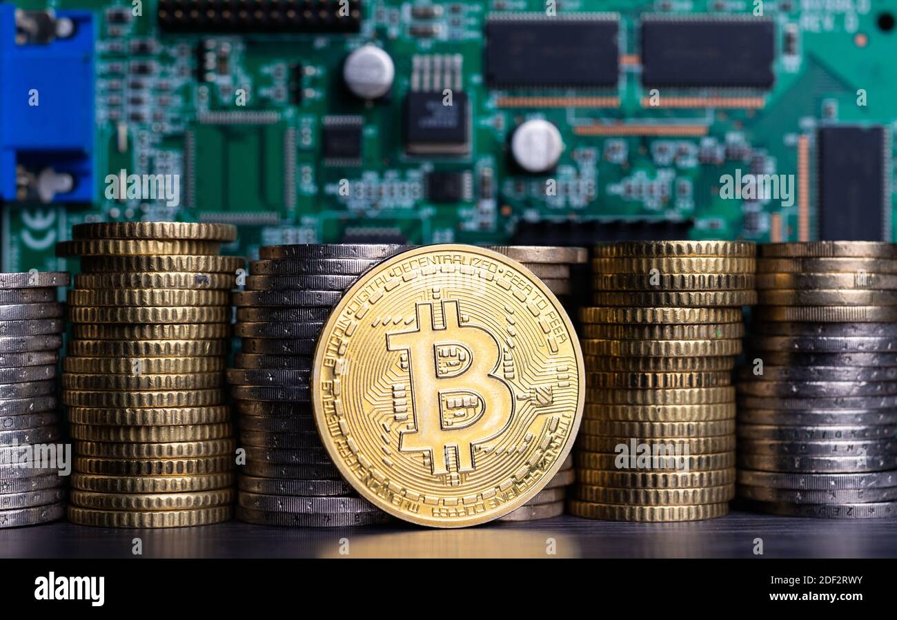 Bitcoin token infront of coins and computer circuits background Stock Photo