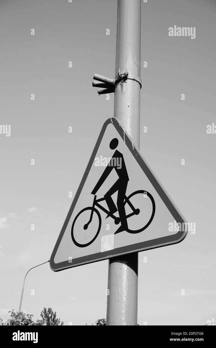 A vertical greyscale closeup shot of a street sign with a bicycle symbol on a pole Stock Photo