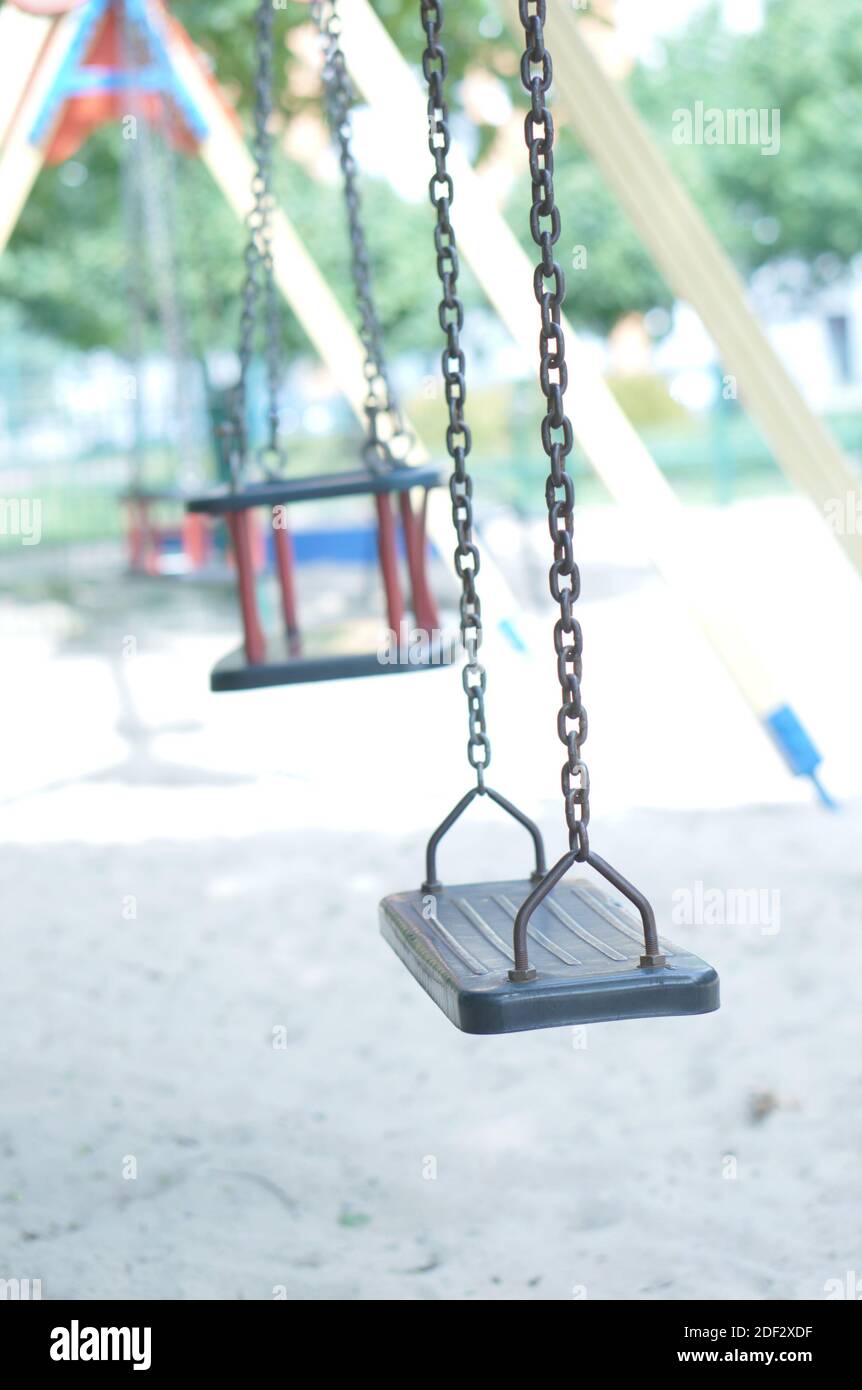 A vertical shot of several swings next to each other in the playground Stock Photo