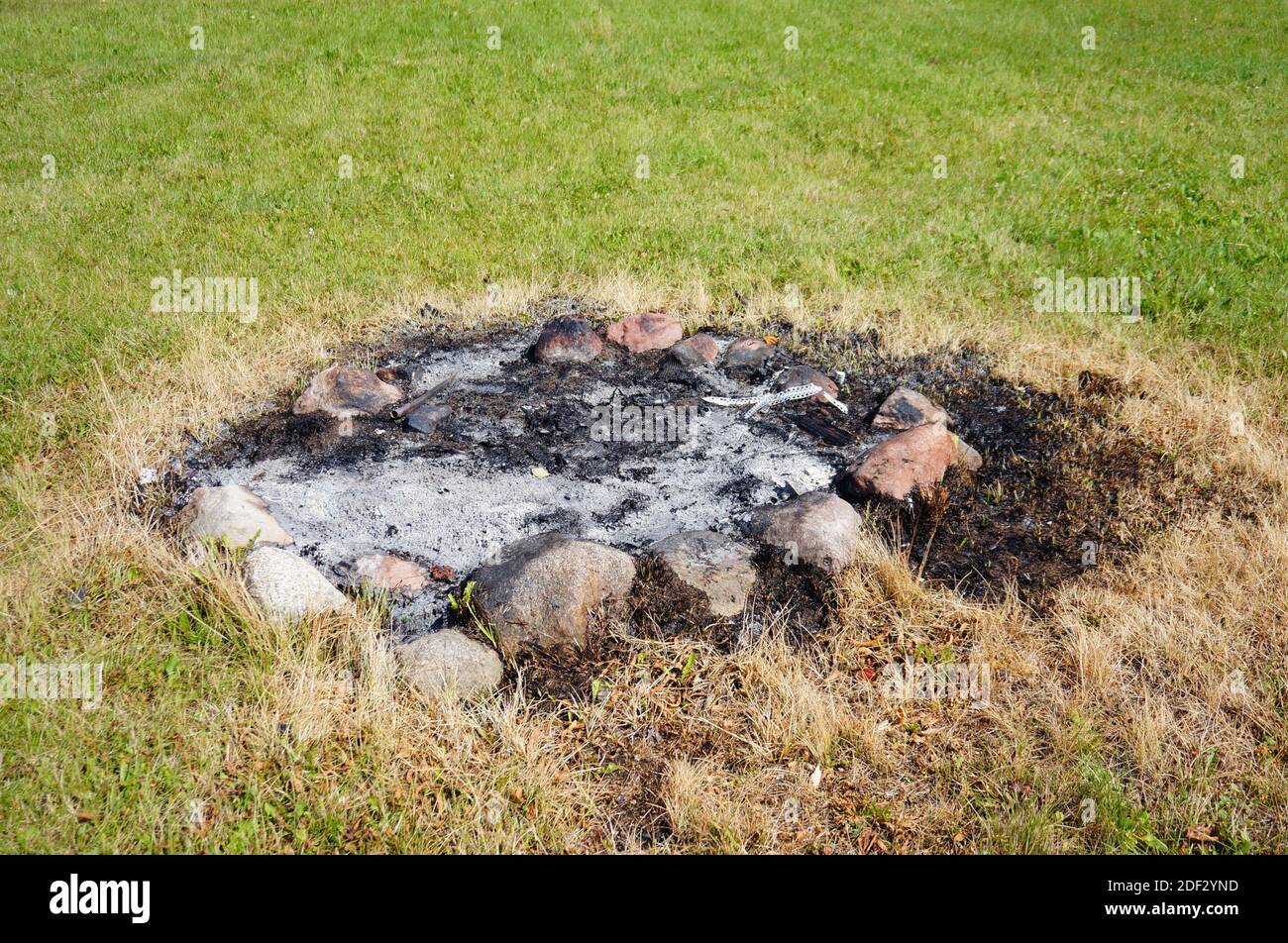 The ashes on a burned fireplace on the green lawn Stock Photo