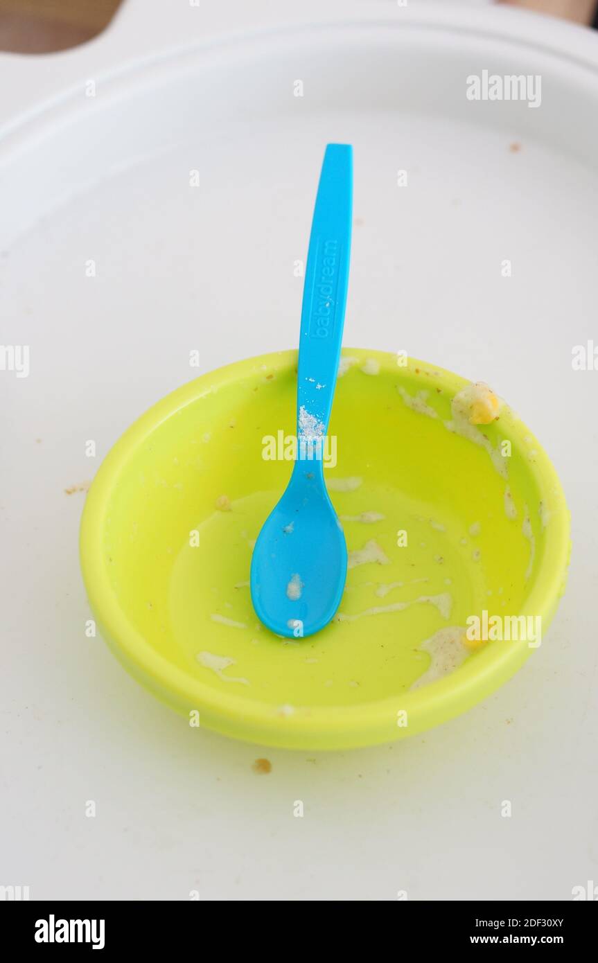 A green bowl and a blue spoon for baby food after eating Stock Photo