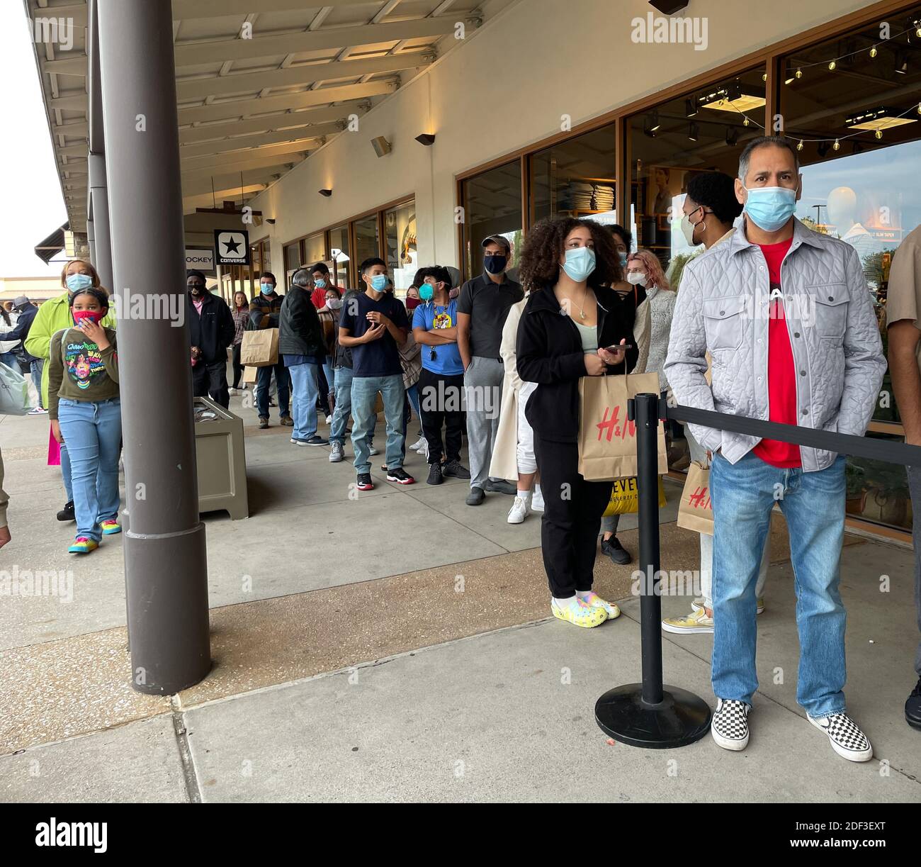 Allen, TX / USA - November 27, 2020: Close up view of people wearing the mask and lining up in front of the store at the Allen Premium Outlets on Blac Stock Photo